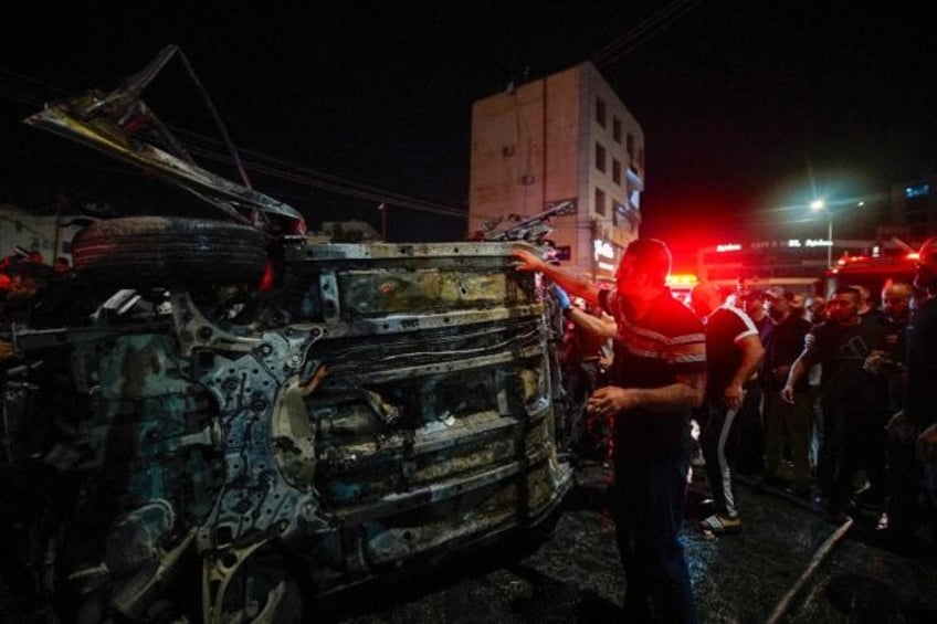 First responders gather around a car hit by an Israeli drone strike in the occupied West B