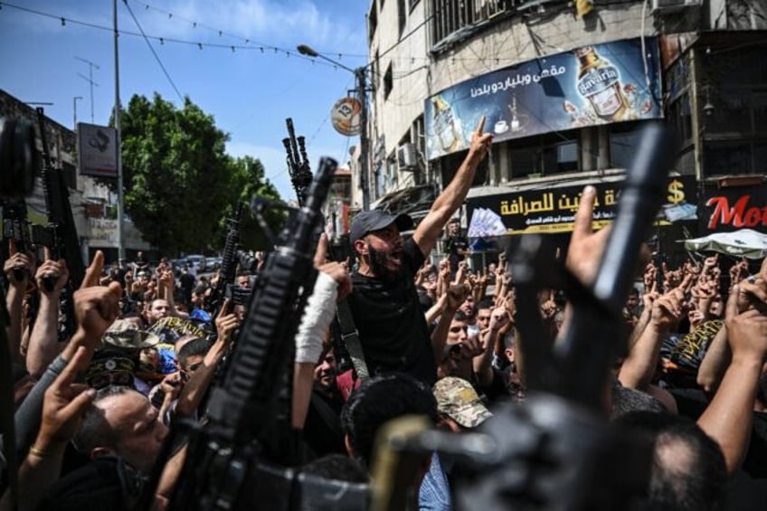 Armed Palestinian militants attend a group funeral of people killed in a raid by Israeli f