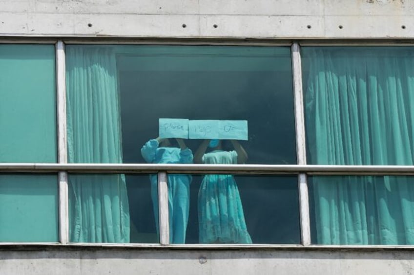 'Please help us,' reads a sign held up to a hotel window in Panama by migrants deported fr