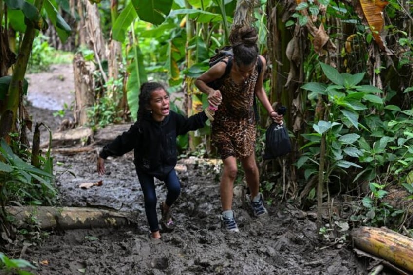 A Venezuelan mother helps her daughter along a muddy path in the Darien in Panama in Octob