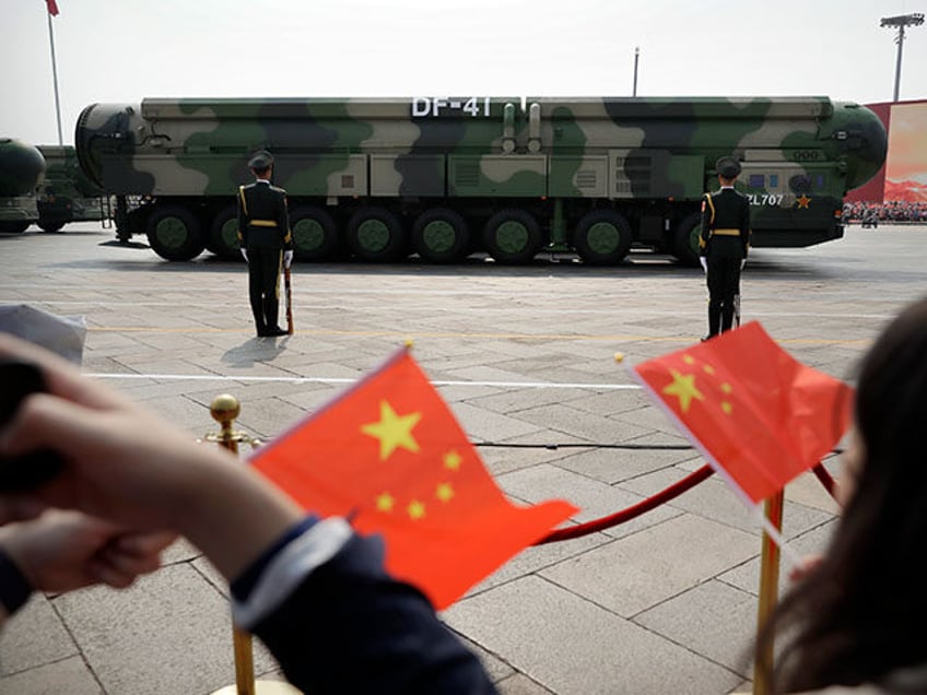 Spectators wave Chinese flags as military vehicles carrying DF-41 nuclear ballistic missil