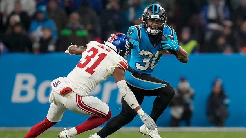 Carolina Panthers running back Chuba Hubbard runs past New York Giants safety Tyler Nubin during the second half of an NFL football game, Sunday, Nov. 10, 2024, in Munich.