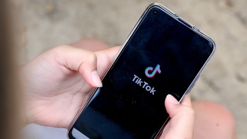 A girl holds a phone with TikTok open