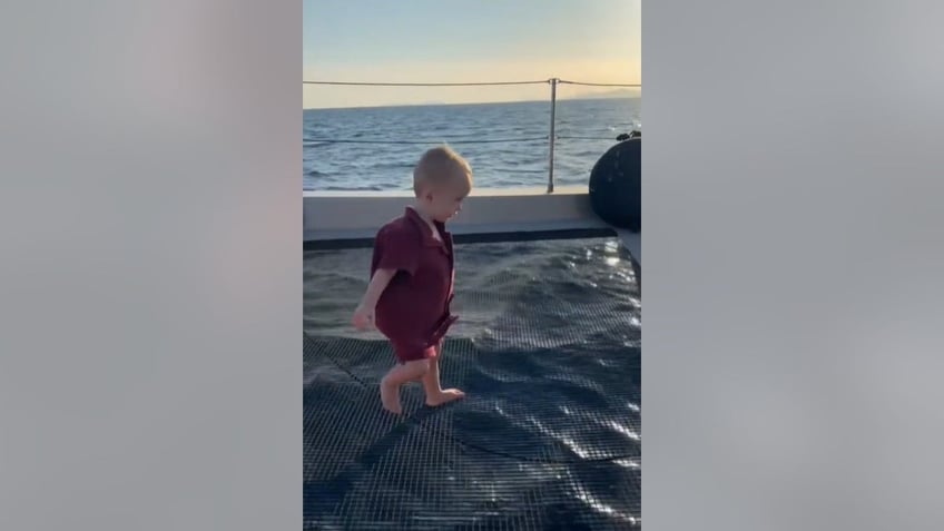 paris hiltons son walking on the netting of a catamaran