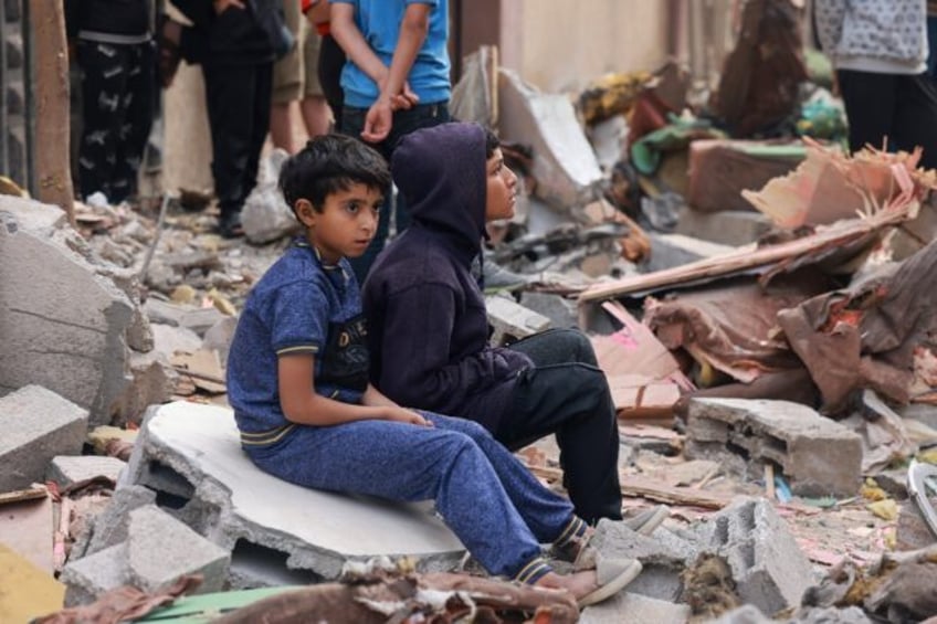 Palestinian boys sit on building rubble following overnight Israeli bombardment in Rafah i