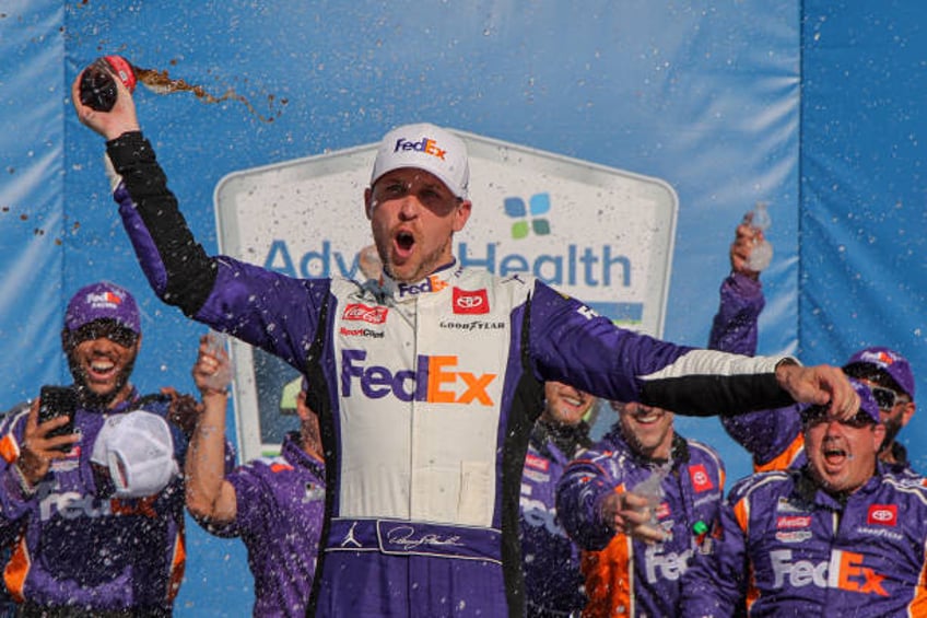 Denny Hamlin, driver of the FedEx Express Toyota, celebrates in victory lane after winning the NASCAR Cup Series Advent Health 400 at Kansas Speedway...