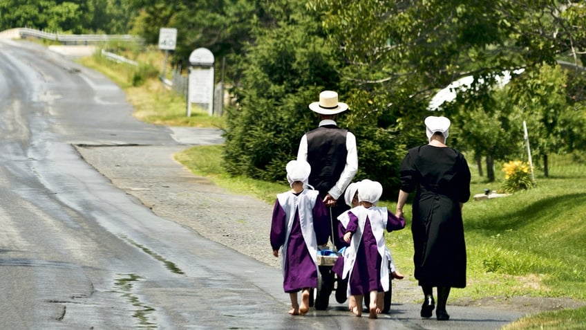 Amish family walking in traditional Amish garb. Their faces are not shown.