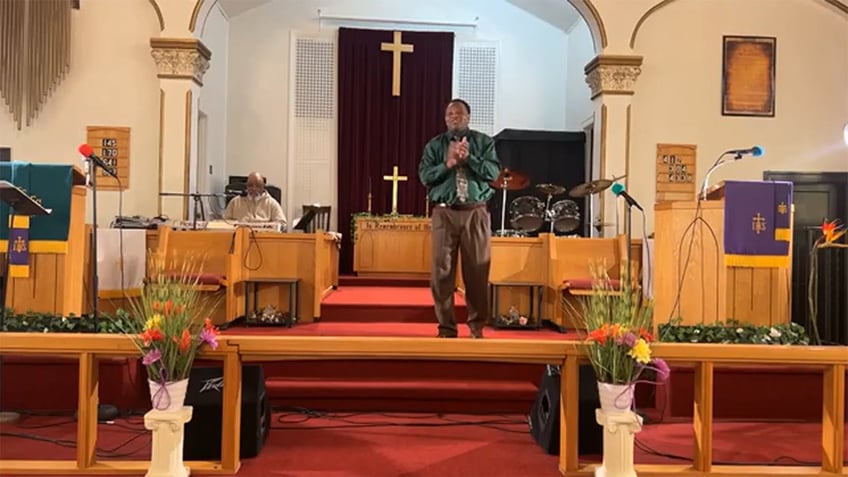 Pastor presses his hands together while delivering sermon