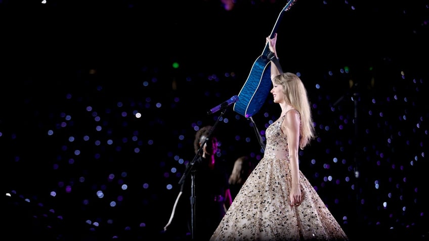 woman holding up guitar on stage