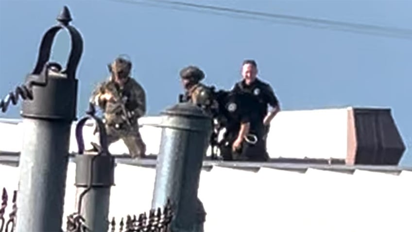 Law enforcement officers stand over the body of would-be Trump assassin, Thomas Crooks on the roof of a building