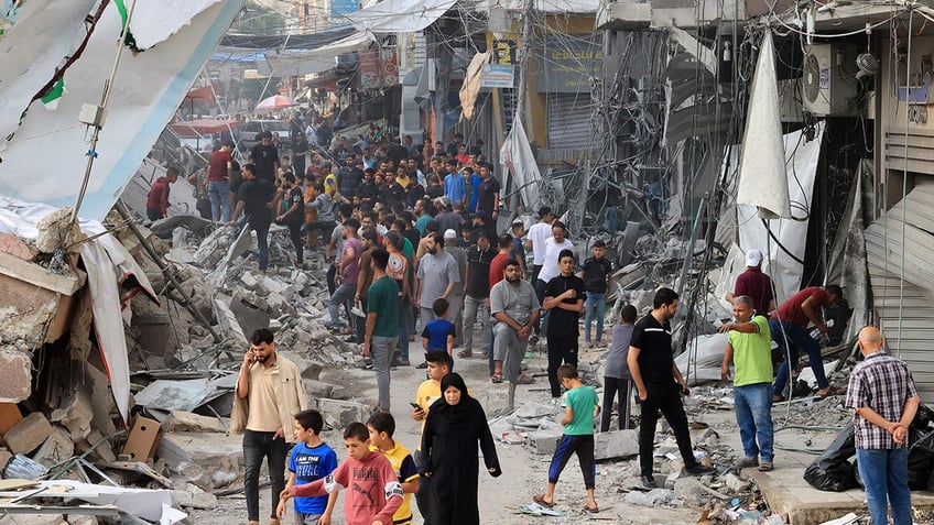 Gazans walking around destroyed buildings