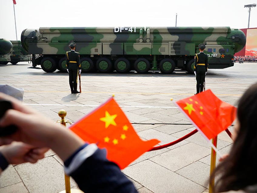 Spectators wave Chinese flags as military vehicles carrying DF-41 nuclear ballistic missil