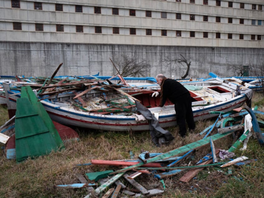 TOPSHOT - An inmates collects wood on a migrant boat to make music instruments as part of