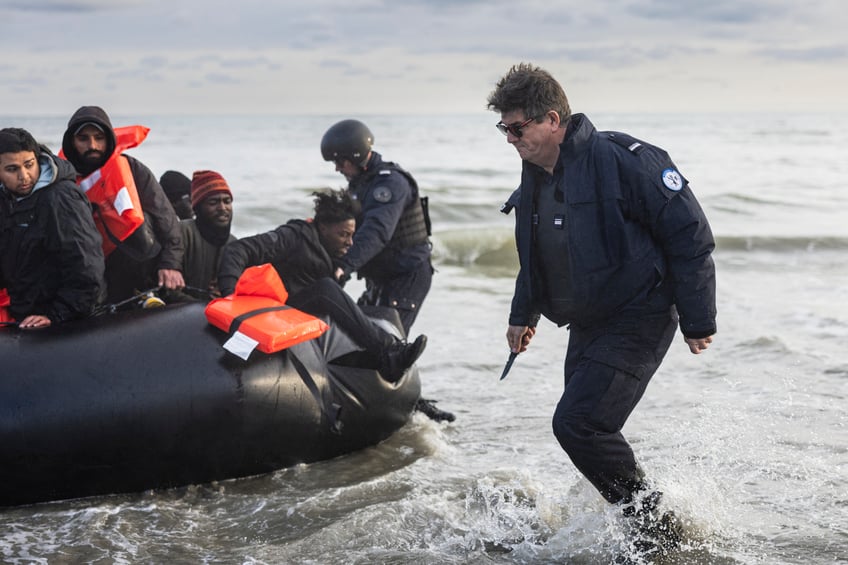 TOPSHOT - French police officers puncture a smuggler's boat with a knife to prevent migrants from embarking in an attempt to cross the English Channelon the beach of Gravelines, near Dunkirk, northern France on April 26, 2024. Five migrants, including a seven-year-old girl, died on April 23, 2024, trying to cross the Channel from France to Britain, local authorities said, just hours after Britain passed a controversial bill to deport asylum seekers to Rwanda. (Photo by Sameer Al-DOUMY / AFP) (Photo by SAMEER AL-DOUMY/AFP via Getty Images)