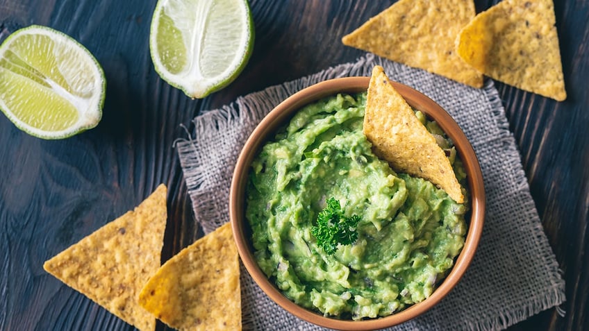 Guacamole bowl with lime and corn chips.