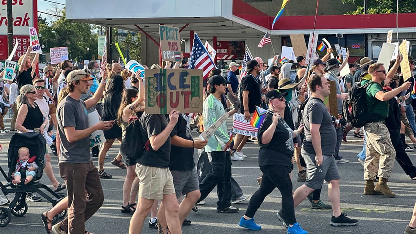 Demonstrators carry signs and chant during a 