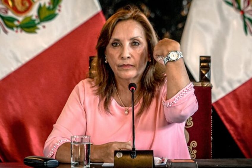 Peru's President Dina Boluarte shows a watch during a press conference, saying it is not a