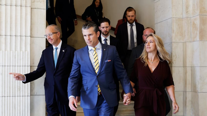 President-elect Donald Trump's nominee to be Secretary of Defense Pete Hegseth, center, and his wife Jennifer Rauchet walk through the Hart Senate Office building on Dec. 3, 2024 in Washington, D.C.