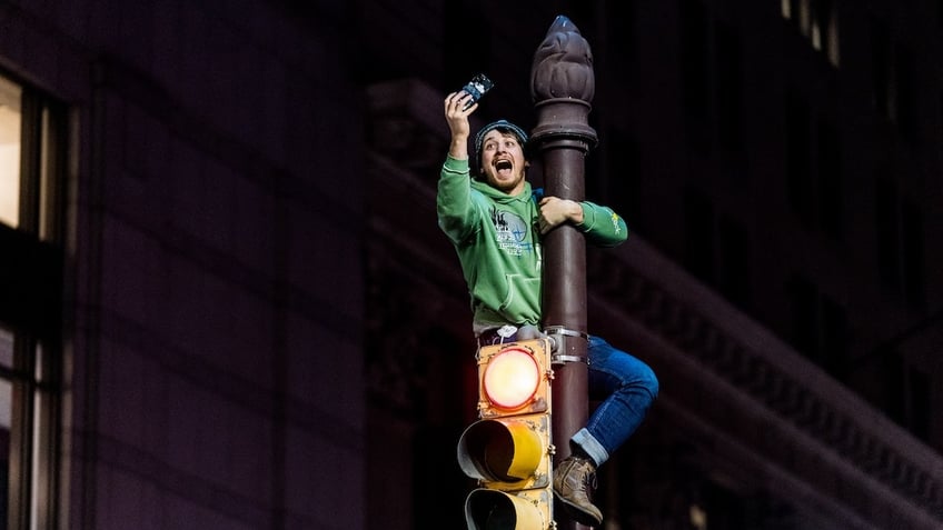 A person climbs a pole following the Philadelphia Eagles NFC Championship win in Philadelphia, Pennsylvania, United States on January 26, 2025. The Philadelphia Eagles defeated the Washington Commanders to advance to the Super Bowl. 