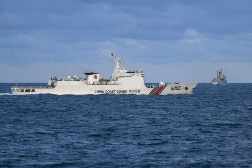 A Chinese Coast Guard ship sails near a Philippine vessel (R) that was part of a convoy of civilian boats in the disputed South China Sea