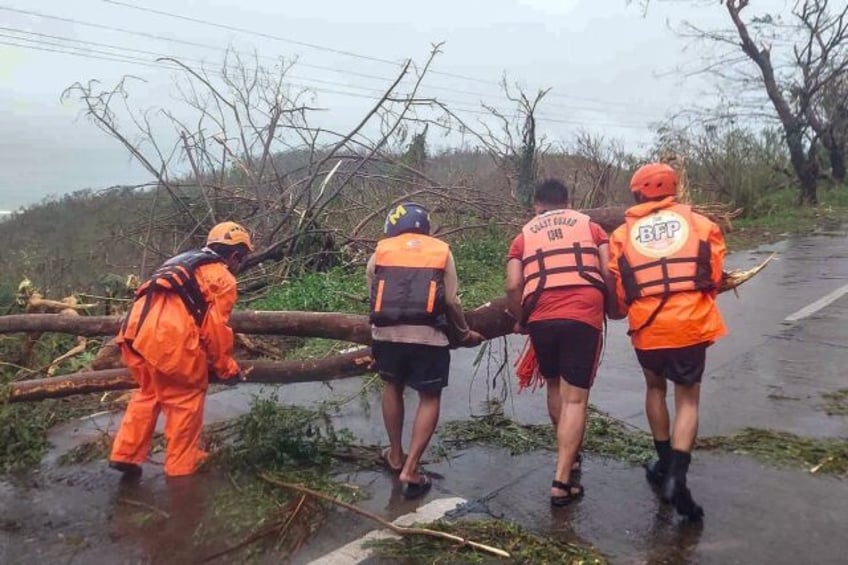 Handout photo from the Philippine Coast Guard shows coast guard personnel clear fallen tre