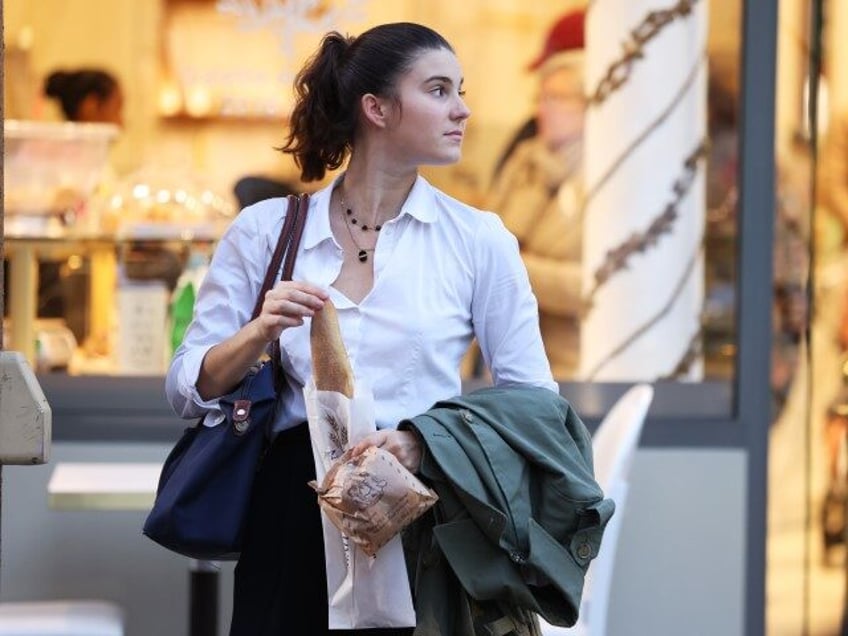 A woman walks out of a bakery with a baguette in her hand in Paris, France, November 7, 20