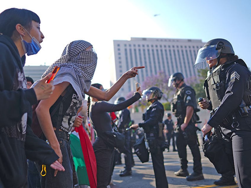 Protesters confront Los Angeles police department personnel in riot gear in downtown Los A