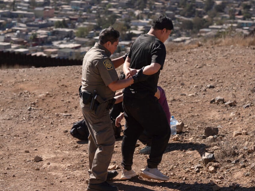 A Border Patrol agent, left, escorts one of four men after the group crossed the border il