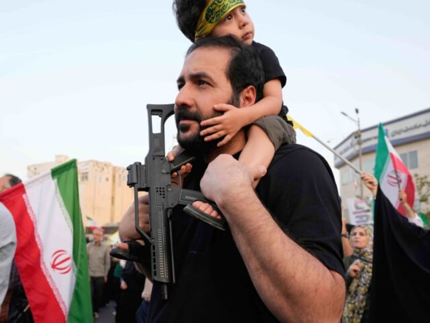 An Iranian protester holds his son with a toy gun in an anti-U.S. and anti-Israeli rally a