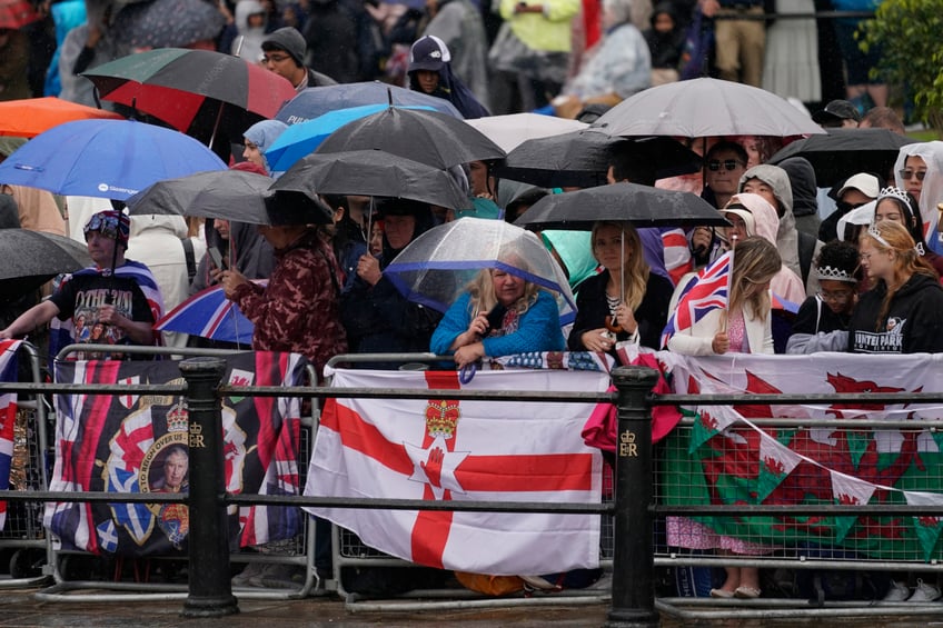 Royal fans shelter under umbrellas as rain falls while they wait for the start of the Trooping the Color ceremony, in London, Saturday, June 15, 2024. Trooping the Color is the King's Birthday Parade and one of the nation's most impressive and iconic annual events attended by almost every member of the Royal Family. (AP Photo/Alberto Pezzali)