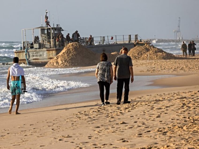 Israelis walk near a US Army vessel at that ran aground at a beach in the coastal city of