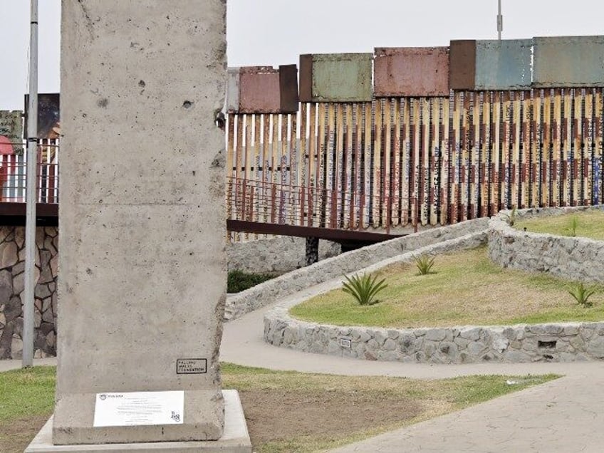 piece of berlin wall placed in mexico near us border barrier as message