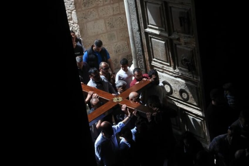 Christian pilgrims carry a wooden cross on the Good Friday procession through the streets