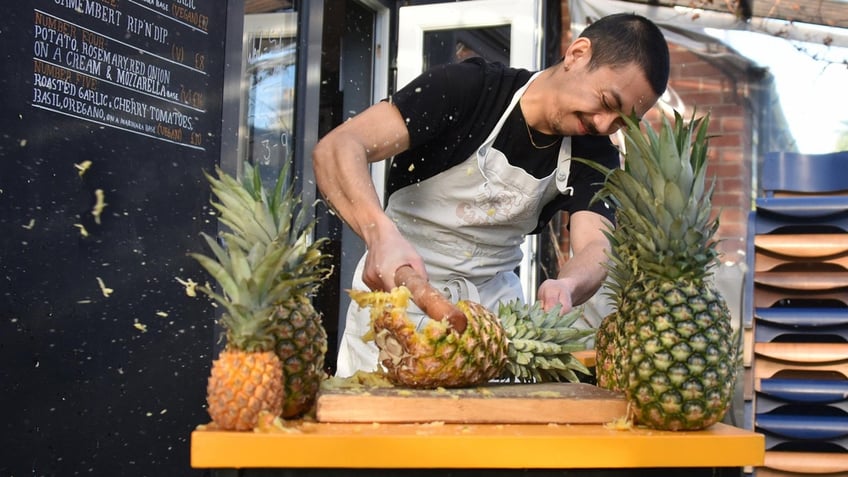 Lupa Pizza head chef and co-owner Quin Jianoran smashes a pineapple.