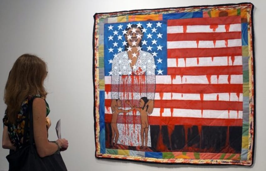 A visitor watches the work of US artist Faith Ringgold, "The Flag is Bleeding #2" (1997) i