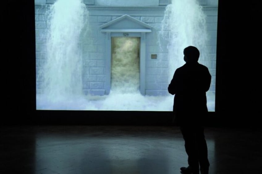 A journalist watches Bill Viola's video 'The Deluge' during a press preview of a 2017 exhi