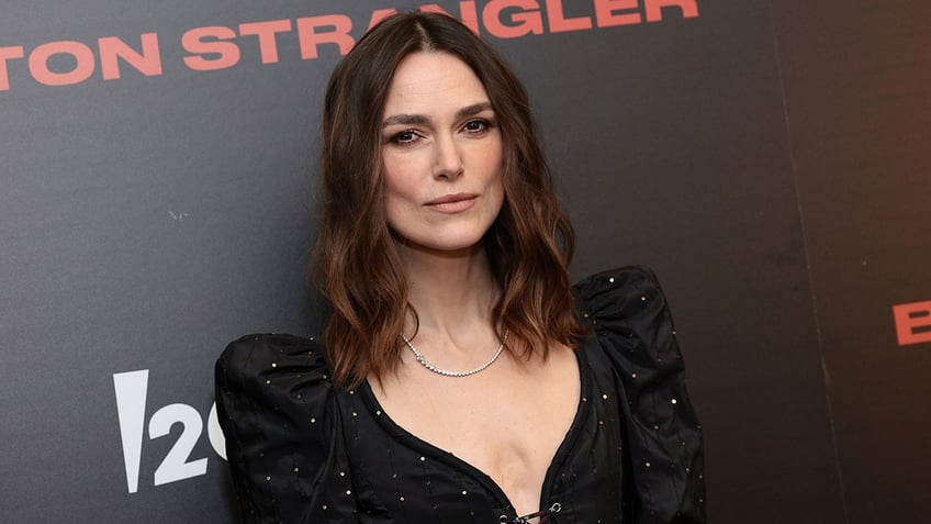 Keira Knightley in a black sparkly dress with poofy shoulders pouts on the carpet