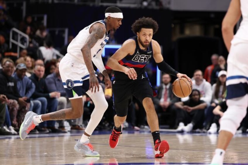 Cade Cunningham of the Detroit Pistons drives around Jaden McDaniels in an NBA victory ove