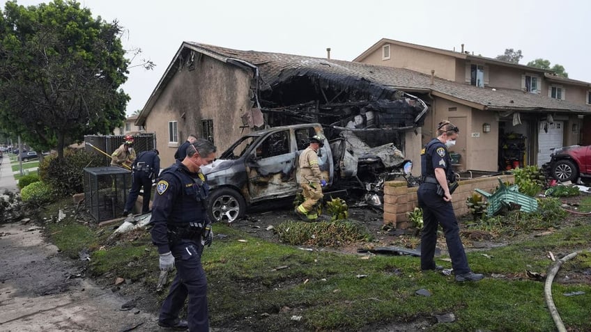 Authorities work the scene of a house where a small plane crashed