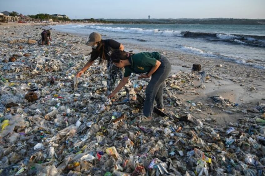 People look through plastic and other debris washed ashore at a beach on Indonesia's resor