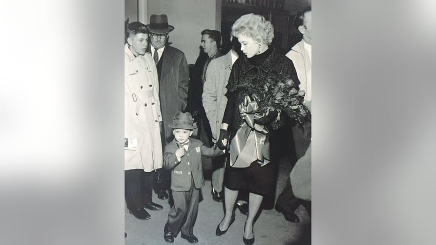 Stella Stevens holding Andrew Stevens hand in a crowd.