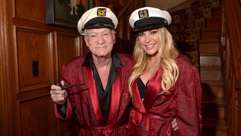 Hugh Hefner and Crystal Hefner wearing matching red robes