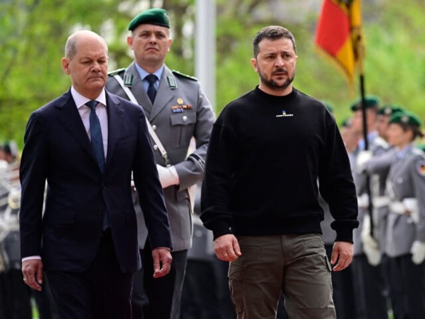 German Chancellor Olaf Scholz (L) and Ukraine's President Volodymyr Zelensky review a mili