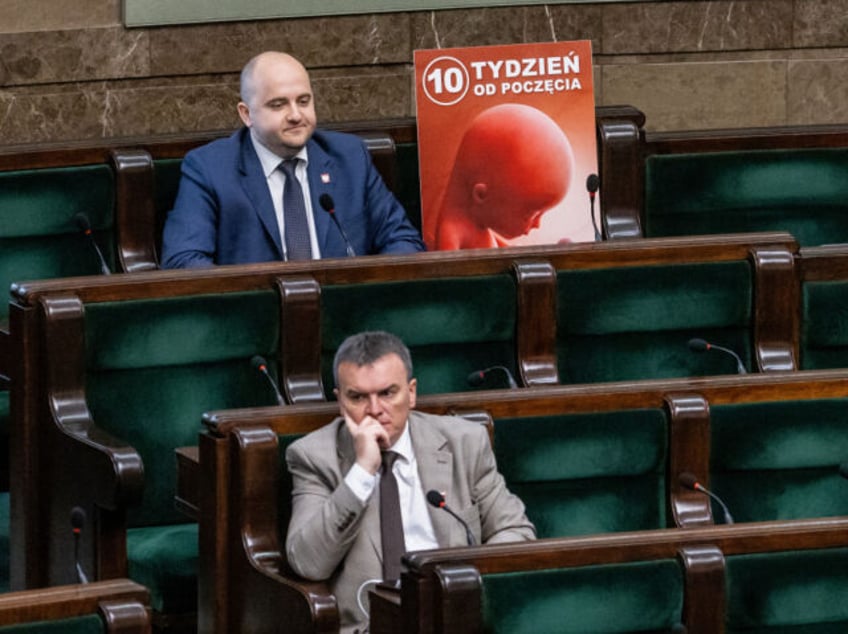 A placard of a pro-life organisation depicting a human fetus is left next to Dariusz Matec