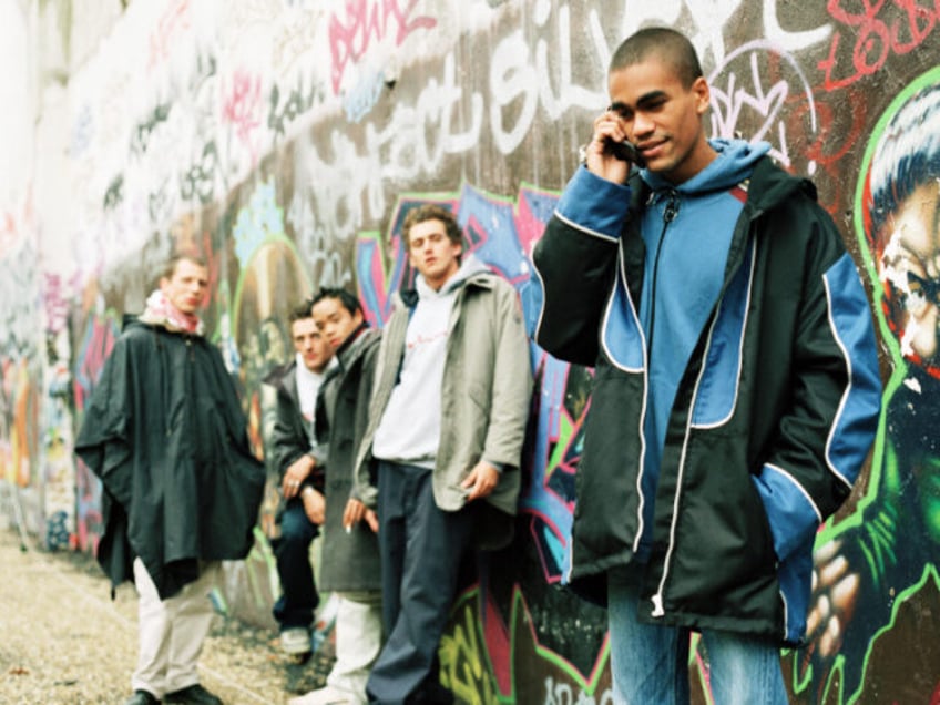 Young men hang out by a graffiti wall.