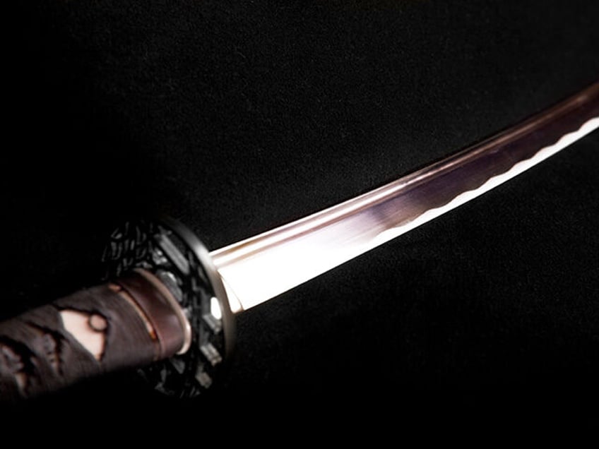 A selectively lit samurai sword on a black background