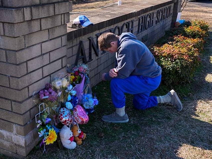 A student kneels in prayer at a memorial for victims of a shooting at Antioch High School,