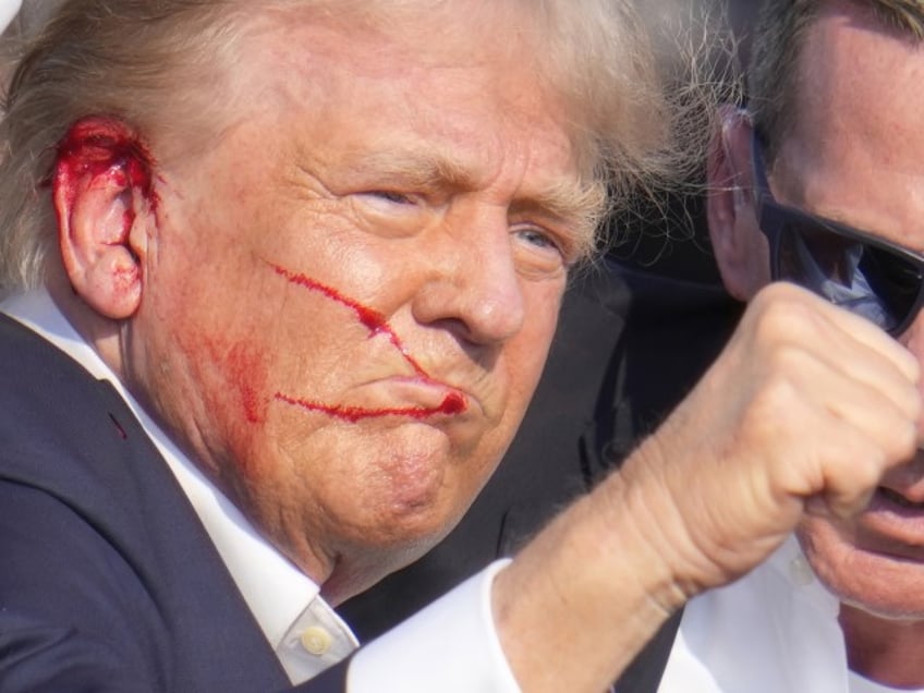 Republican presidential candidate former President Donald Trump gestures while surrounded by U.S. Secret Service agents as he is helped off the stage at a campaign rally in Butler, Pa., Saturday, July 13, 2024. (Gene J. Puskar/AP)