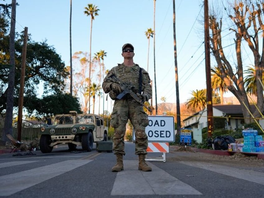 A member of the National Guard stands in front of a road closed due to the Eaton Fire on M