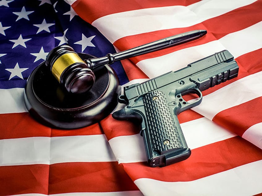 Wooden judge gavel and black color gun over USA flag.